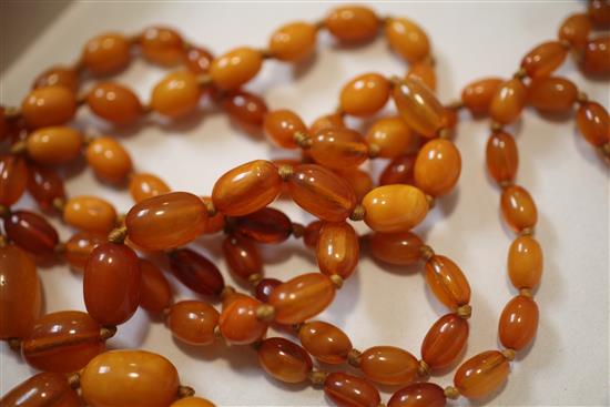 A long single strand graduated oval amber bead necklace, 70in.